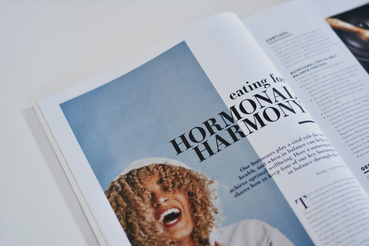 Frau lacht beim Lesen eines Magazinartikels über hormonelle Harmonie.